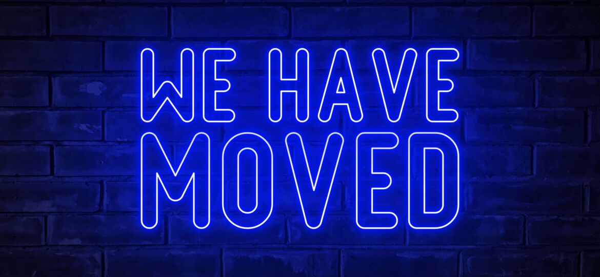 We have moved - blue neon light word on brick wall background