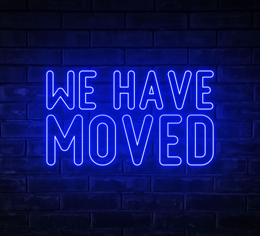 We have moved - blue neon light word on brick wall background